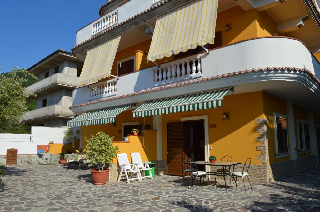 a yellow building with chairs and a table in front of it at Residenza Eolo in Tropea