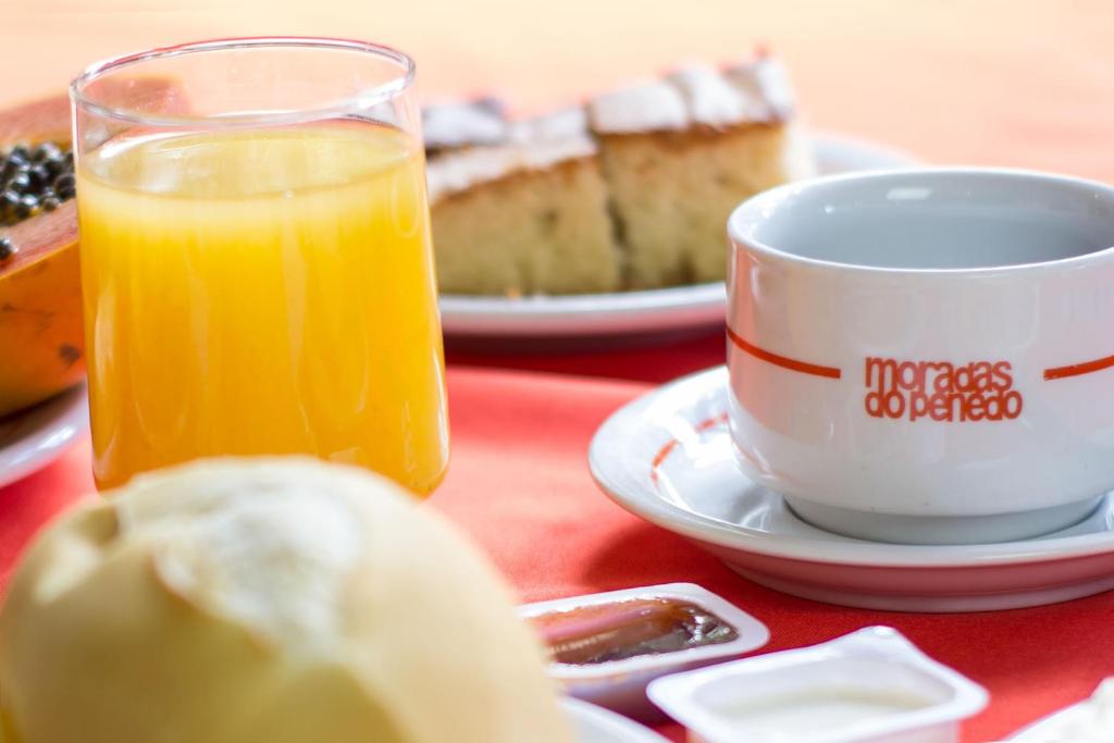 uma mesa com uma chávena de sumo de laranja e um pedaço de bolo em Hotel Moradas do Penedo em Penedo