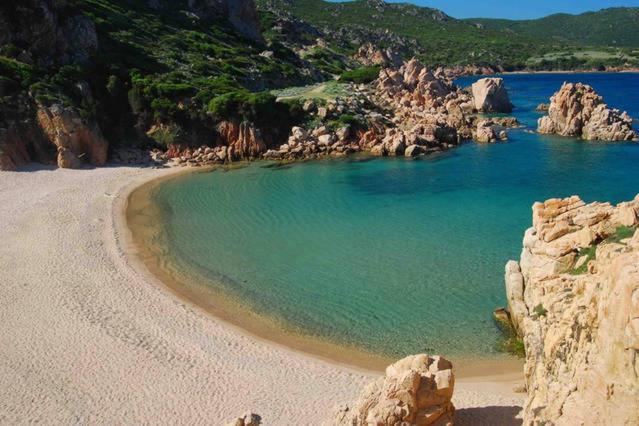 a beach with rocks and blue water and a rocky shore at Holiday home Isola Rossa in Isola Rossa