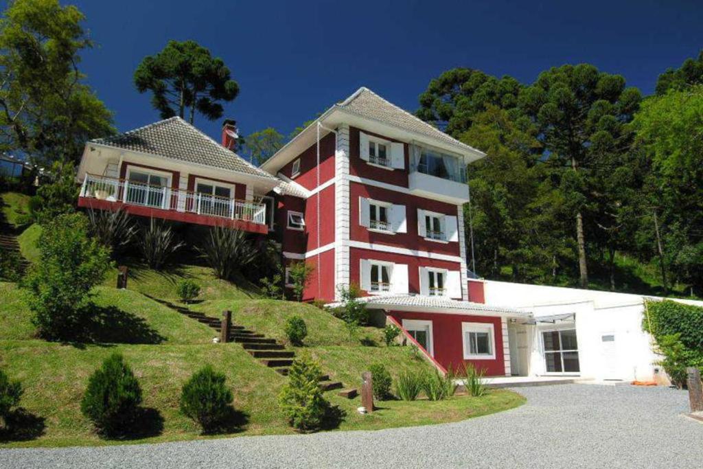 une maison rouge et blanche au sommet d'une colline dans l'établissement Pousada Atalaia Premium, à Campos do Jordão