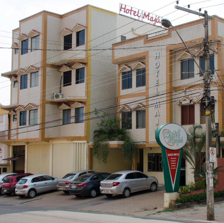 a hotel with cars parked in front of a building at Hotel Majú in Rio Branco