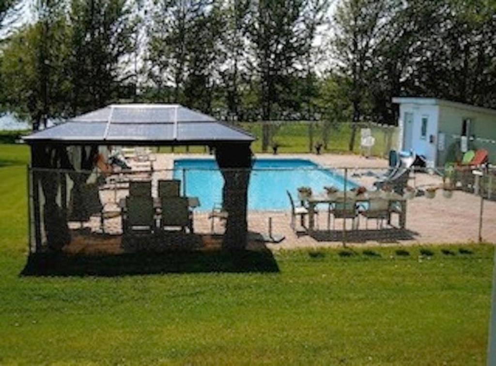 een prieel met een tafel en stoelen naast een zwembad bij Doran Bay Resort in Iroquois