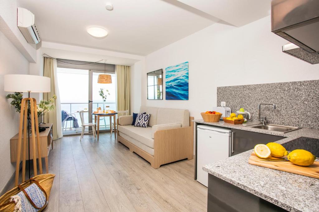 uma cozinha e sala de estar com um sofá e uma mesa em Pierre & Vacances Blanes Playa em Blanes