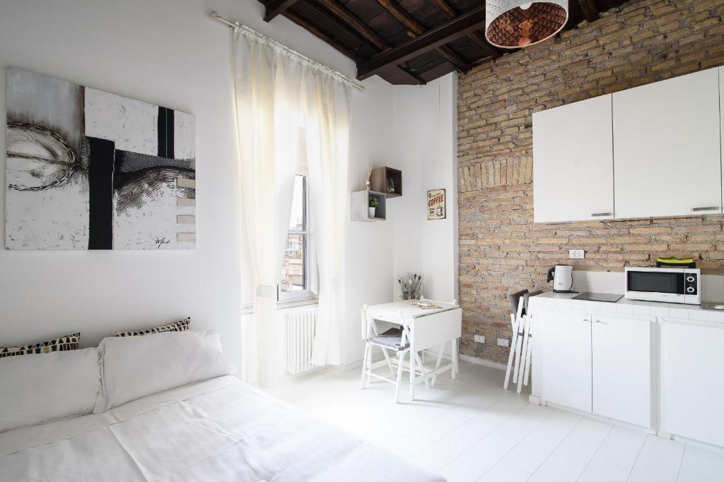 a white room with a bed and a kitchen at White Ostilia Apartments in Rome