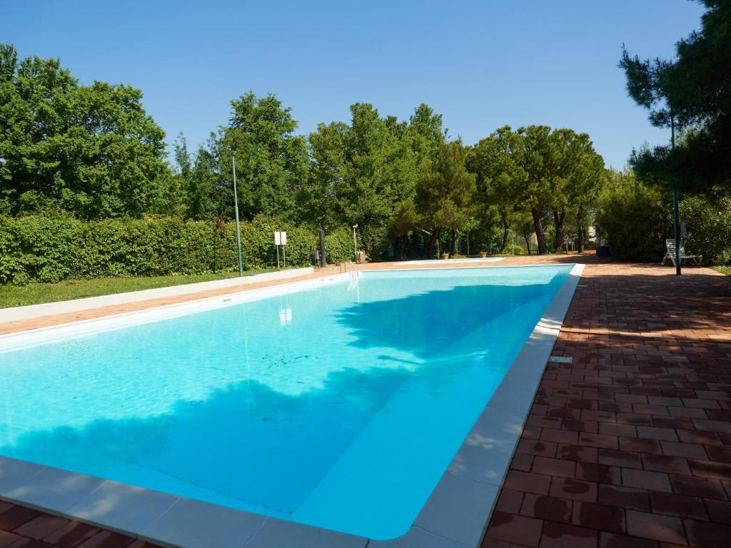 a large blue swimming pool with trees in the background at Appartamento Anna in Desenzano del Garda