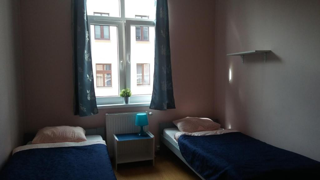 two beds in a small room with a window at Hostel Imbir in Toruń