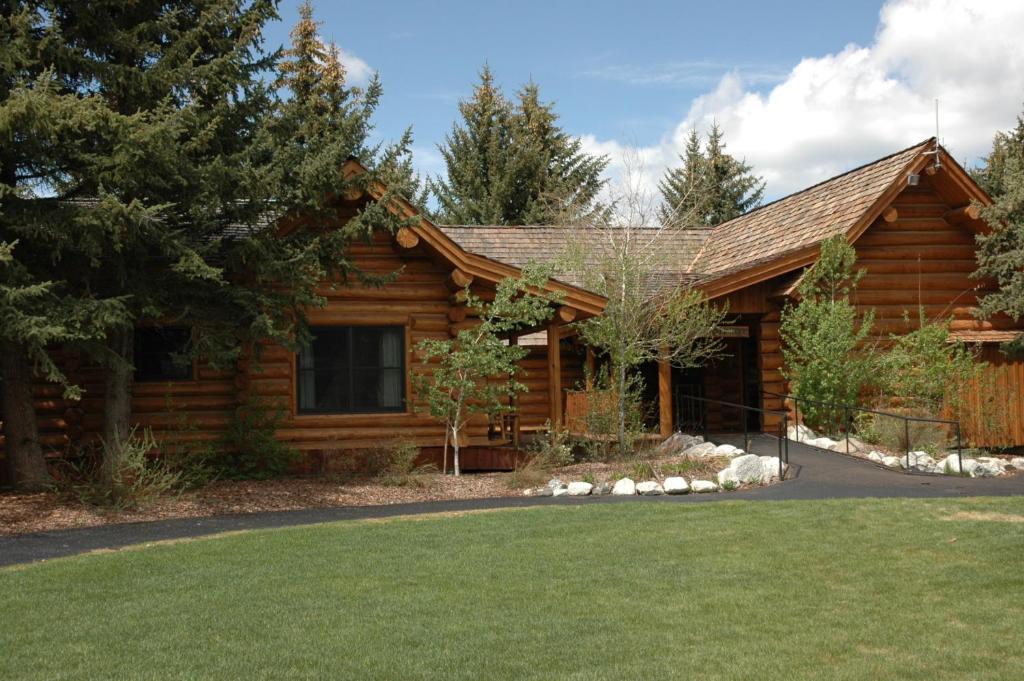 a log cabin with a lawn in front of it at The Hatchet Resort in Moran