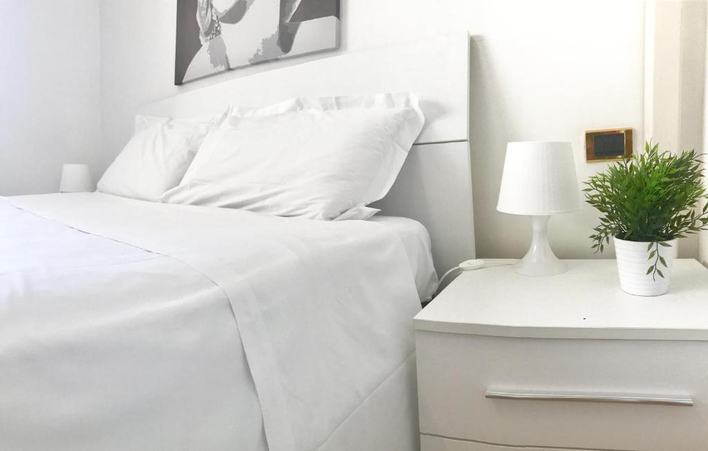 ローマにあるGiulio Cesare luxury apartmentの白いベッド(白いシーツ付)、ナイトスタンドの植物