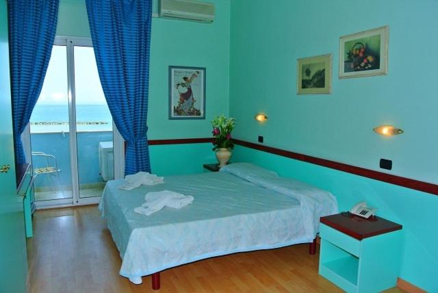 a blue bedroom with a bed and a window at Hotel Mirage in Lido di Classe