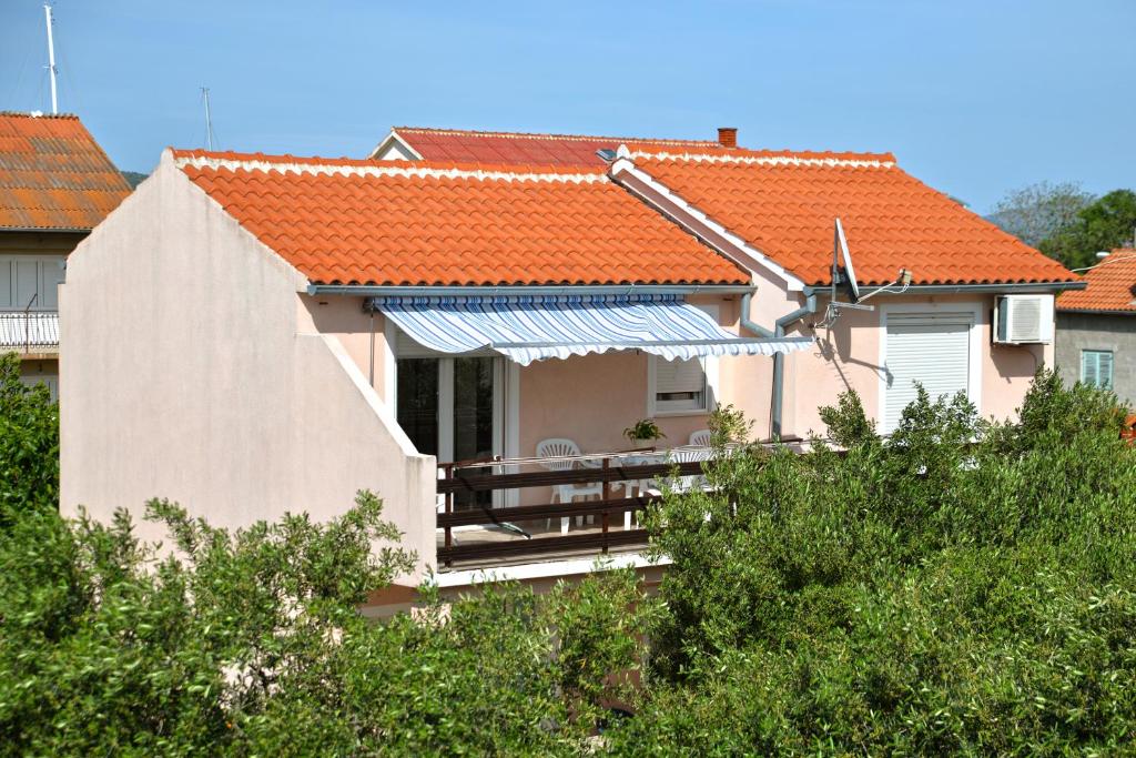 una casa con tetto arancione e portico di Apartmani Šime a Betina