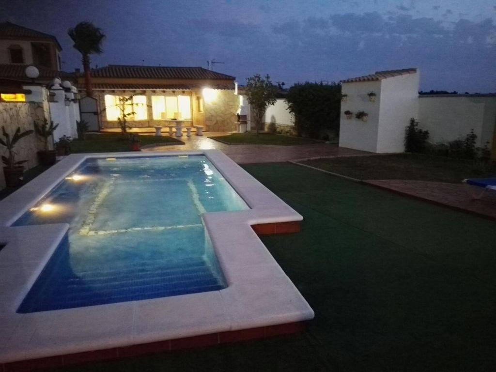 a swimming pool in the yard of a house at night at Villa Rosal- Solo familias y parejas in Conil de la Frontera