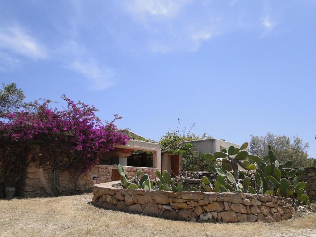 a house with a stone wall and purple flowers at Casa Andrea in Sant Francesc Xavier