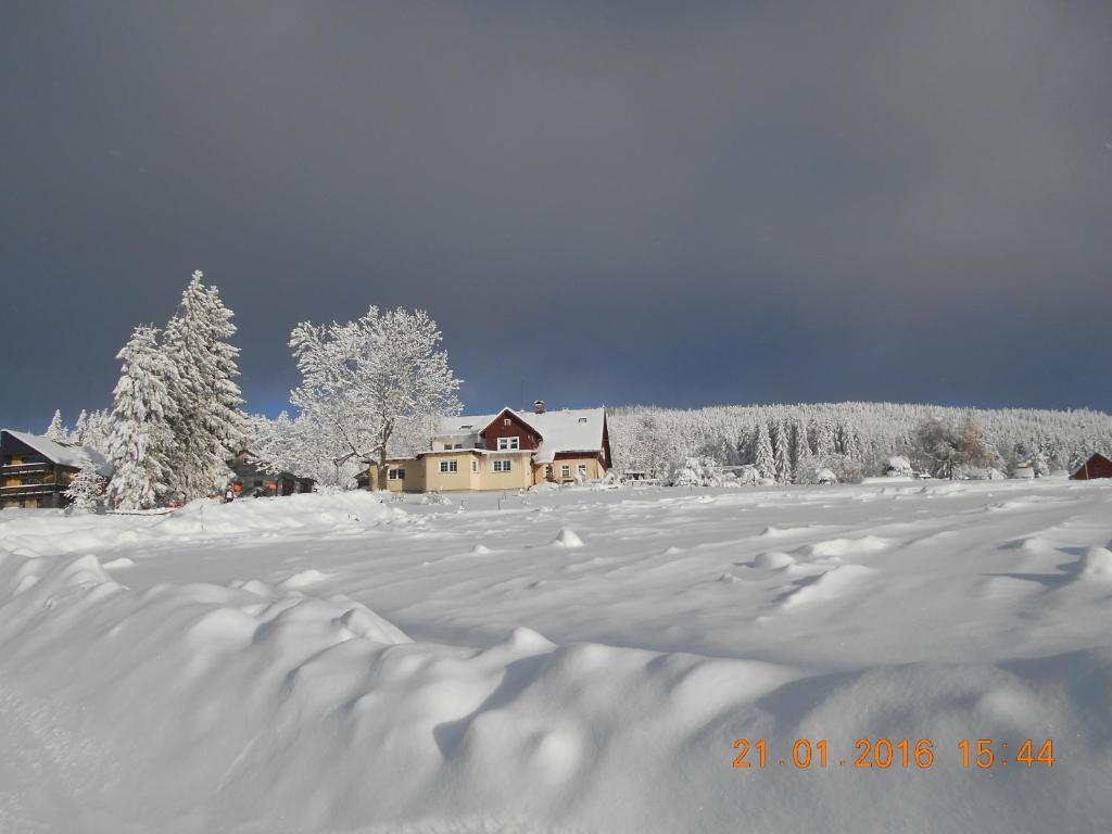 um campo coberto de neve com uma casa ao fundo em U Jeriů em Benecko
