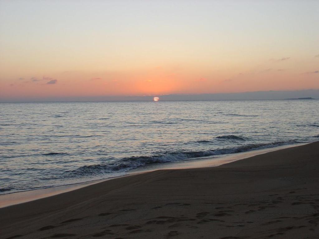 a sunset over the ocean with a sandy beach at Tony's Apartments in Agios Georgios
