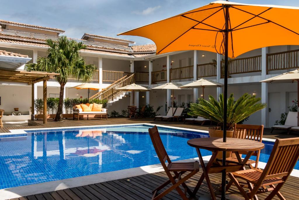 Hotel Maui Maresias في ماريسياز: طاولة مع مظلة بجانب مسبح