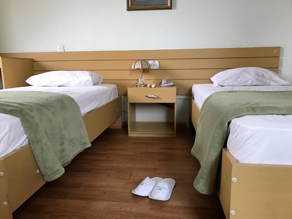 um quarto com duas camas e uma mesa com mesa de cabeceira em Hotel Family em São Paulo