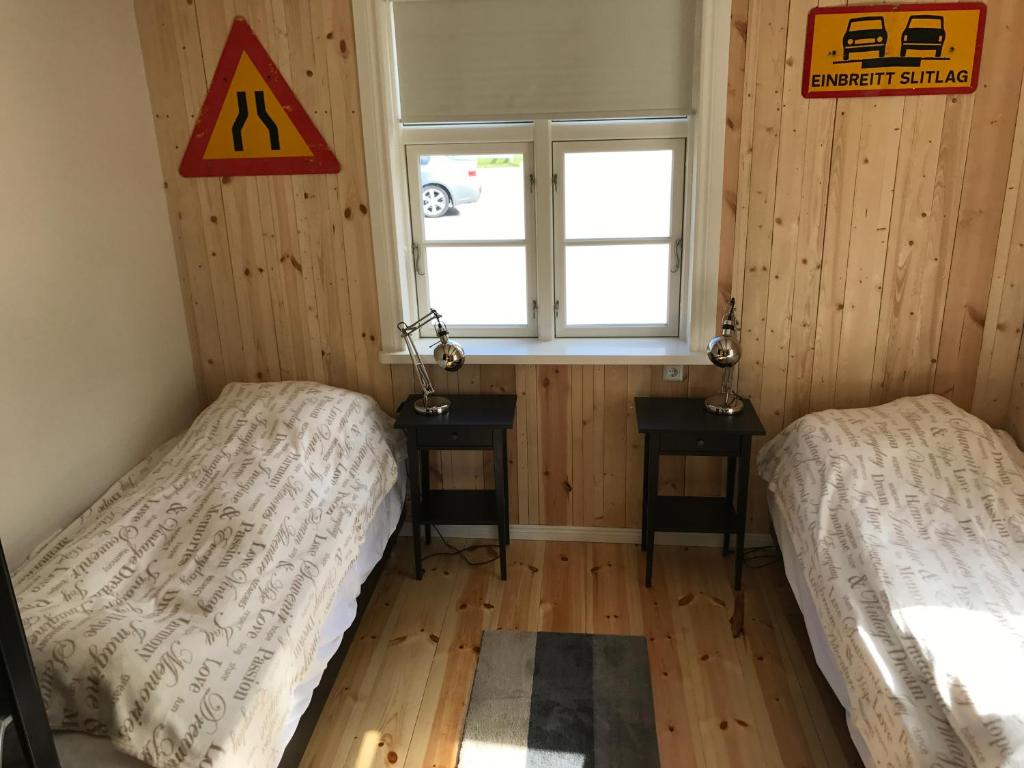 two beds in a room with wooden walls and a window at Tangs in Ísafjörður
