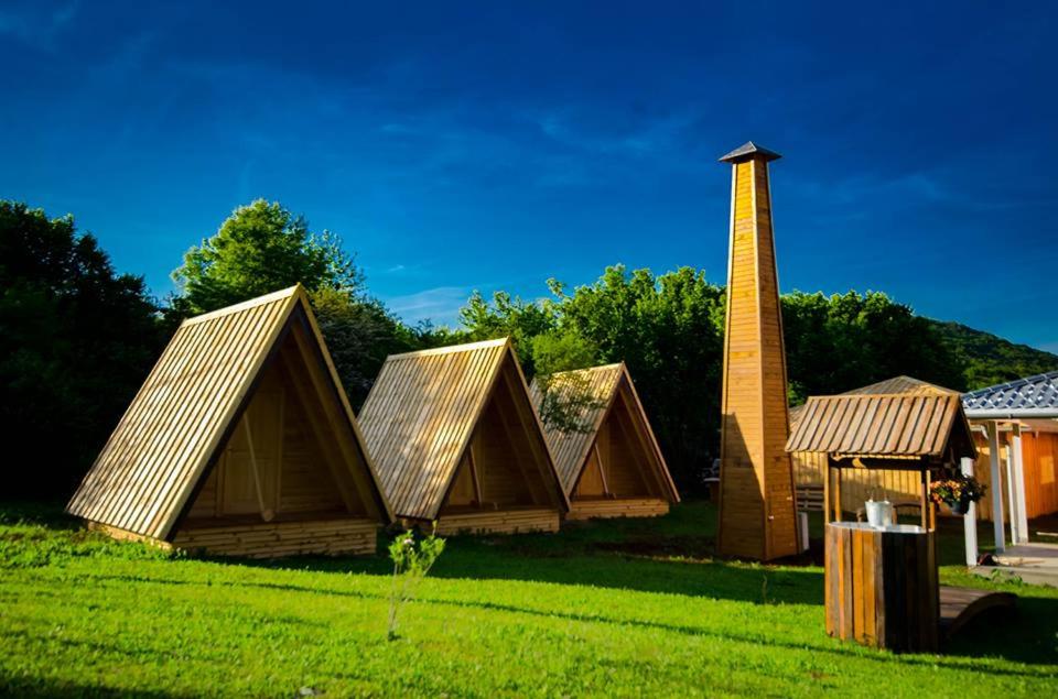 a group of homes with a chimney in the grass at Rooms & Glamping Lana Haus in Ličko Petrovo Selo