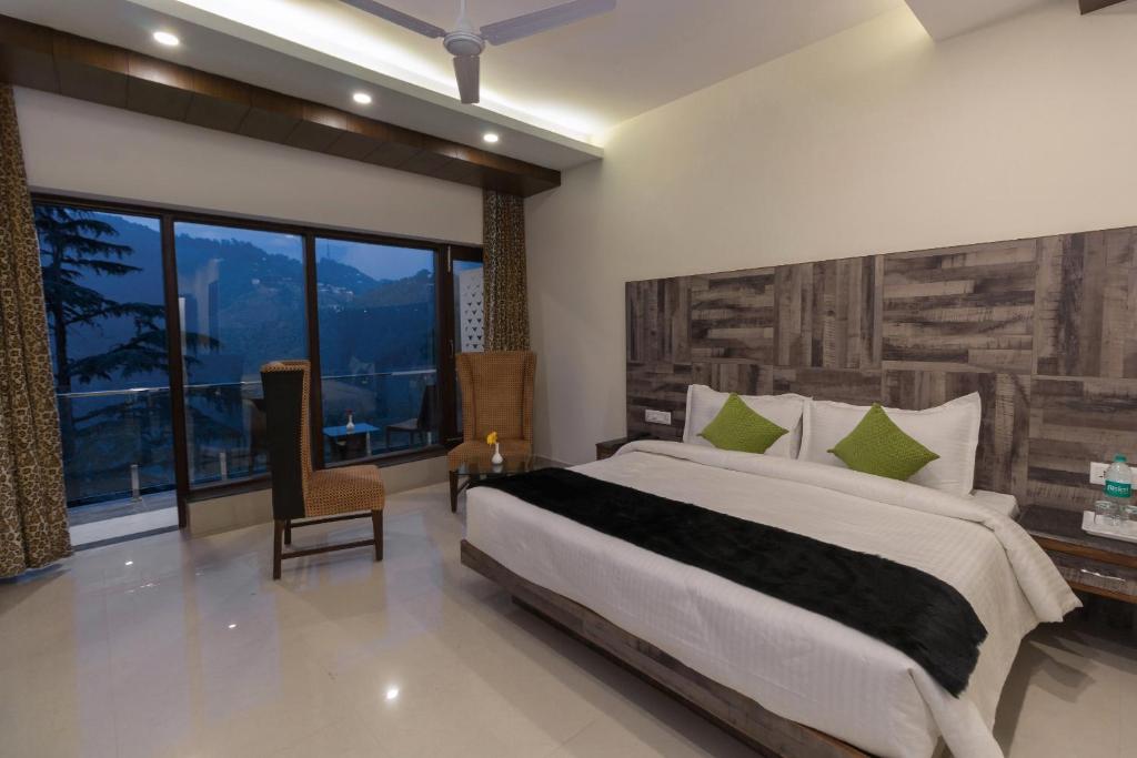 a bedroom with a large bed and a large window at Hotel Seven Oaks in Mussoorie