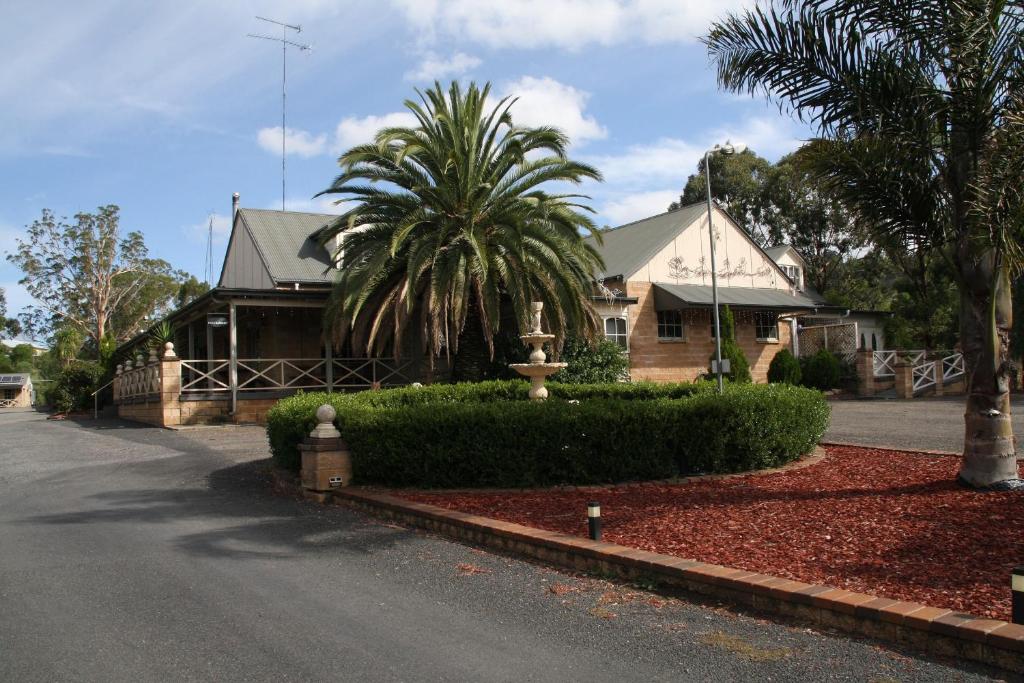 a house with a palm tree next to a street at Picton Valley Motel Australia in Picton