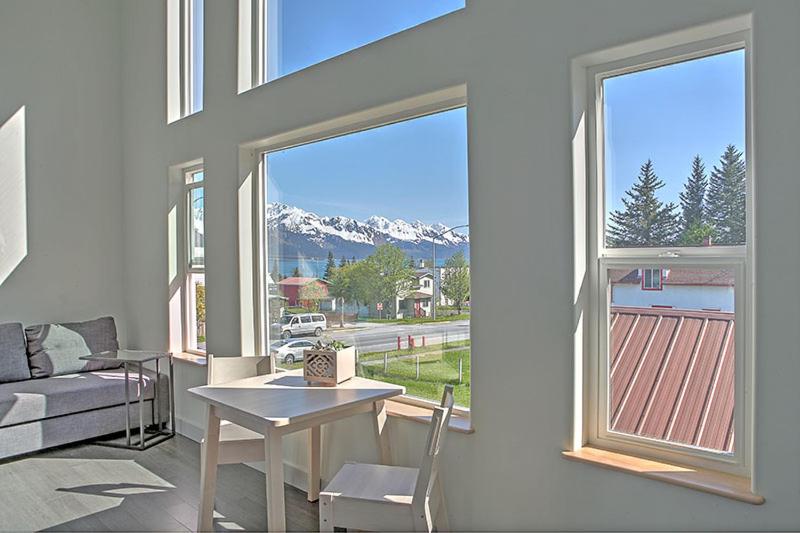 ein Wohnzimmer mit einem Tisch und einem großen Fenster in der Unterkunft The Vue B&B in Seward