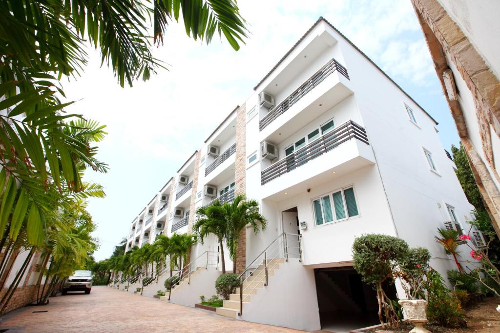 un edificio blanco con palmeras delante en Hidden Palm Pool Villas, en Norte de Pattaya