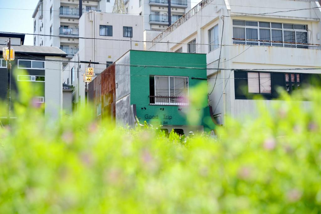 a green building in front of some buildings at Good Trip Hostel & Bar in Odawara