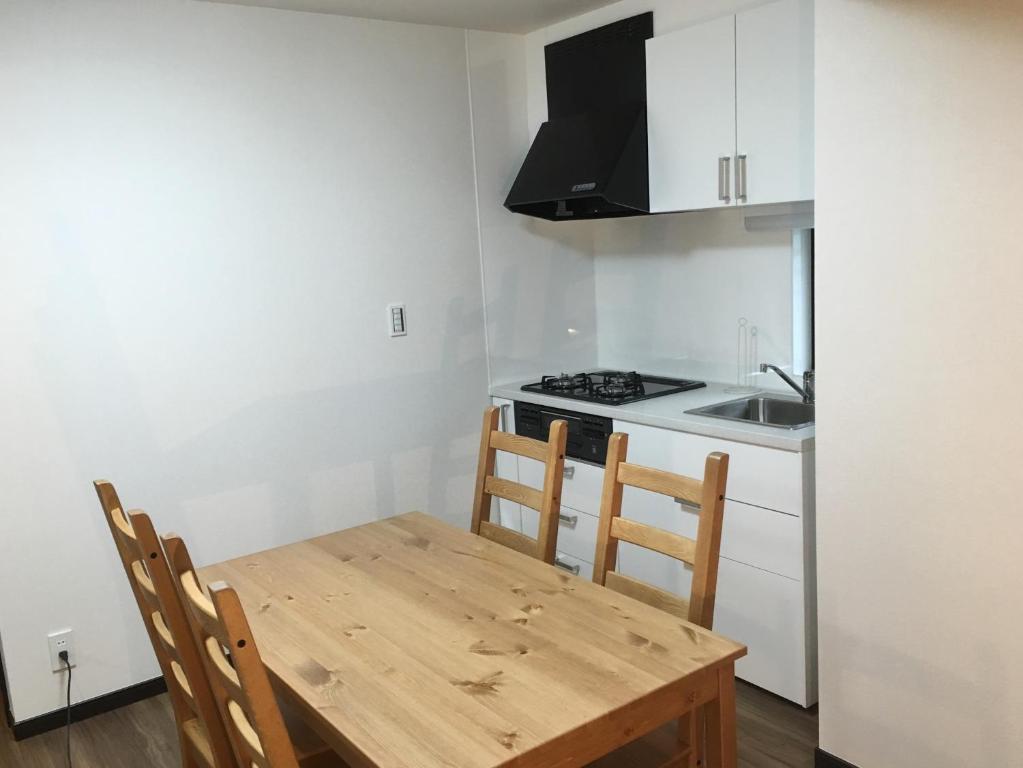a kitchen with a wooden table and chairs and a stove at TIMES INN 2F in Tokyo
