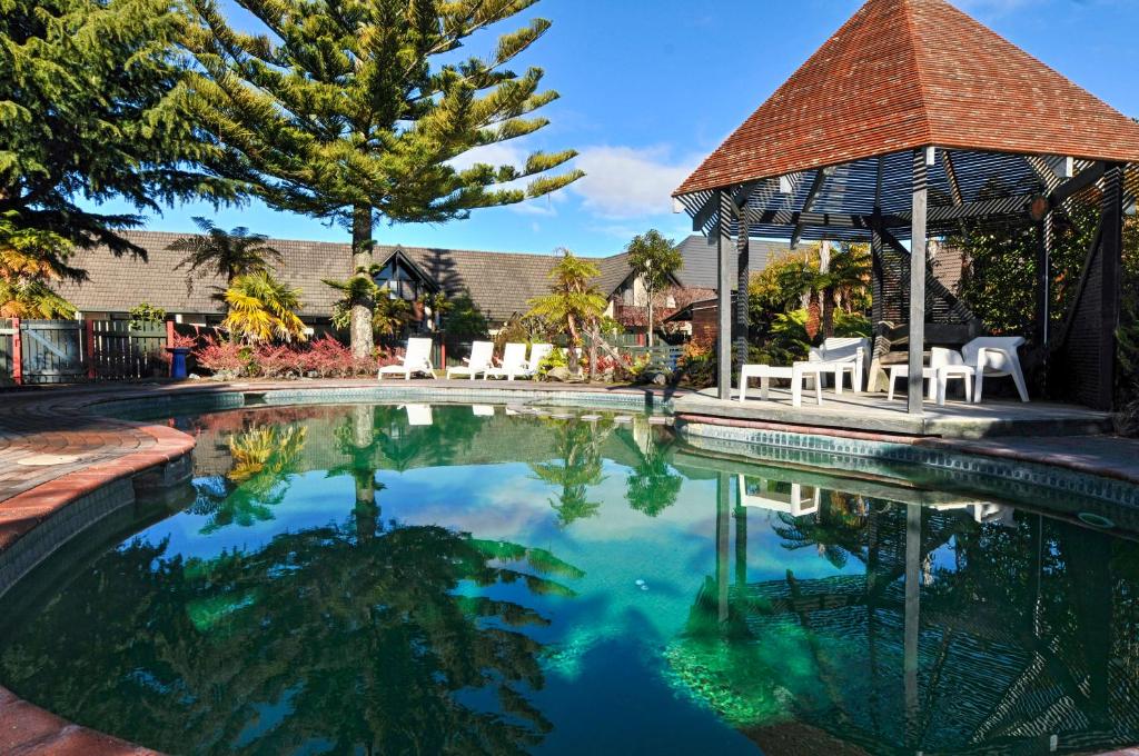a swimming pool with chairs and a gazebo at Wylie Court Motor Lodge in Rotorua