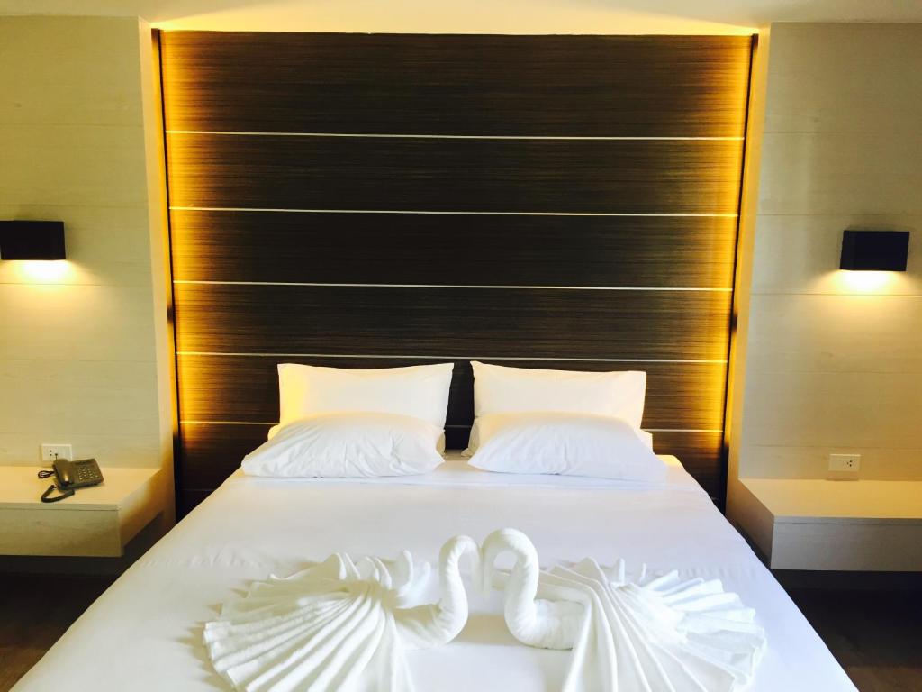 due cigni seduti sopra un letto bianco di Merdelong Hotel a Phatthalung