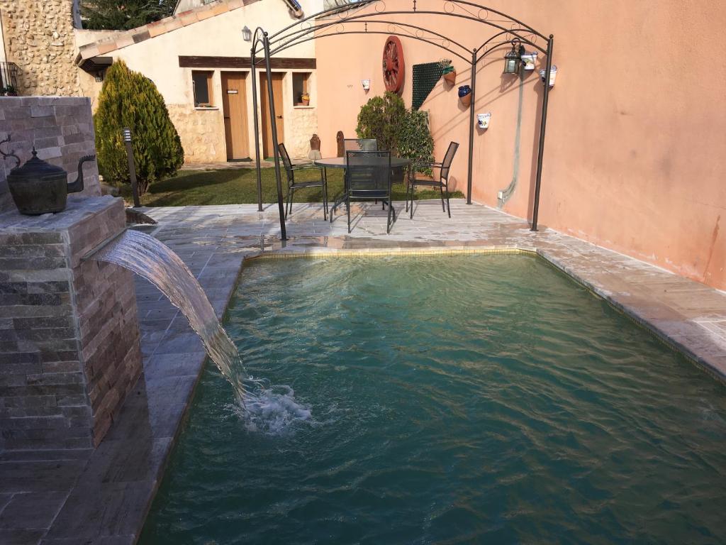 a swimming pool with a water fountain in a yard at Casa Rural La Gesta in Jadraque