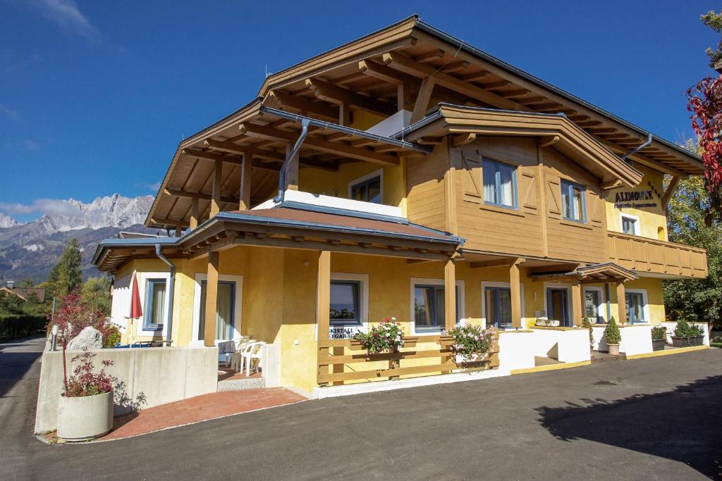 uma grande casa de madeira com montanhas ao fundo em Alimonte Romantic Appartements em Sankt Johann in Tirol