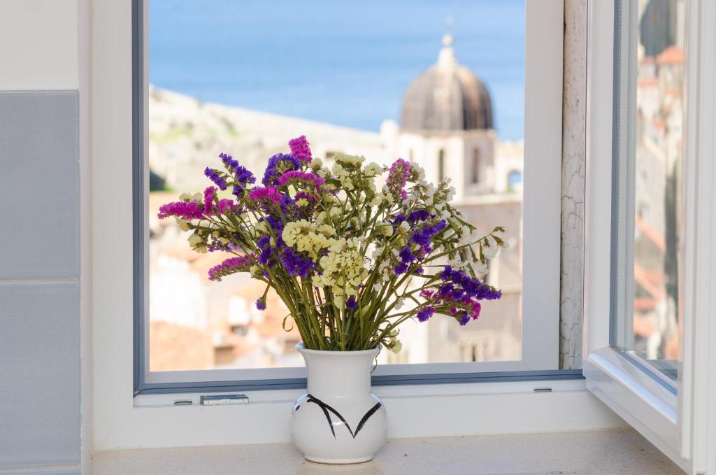 a vase with purple flowers sitting on a window sill at Sea View Studio Positive Place in Dubrovnik