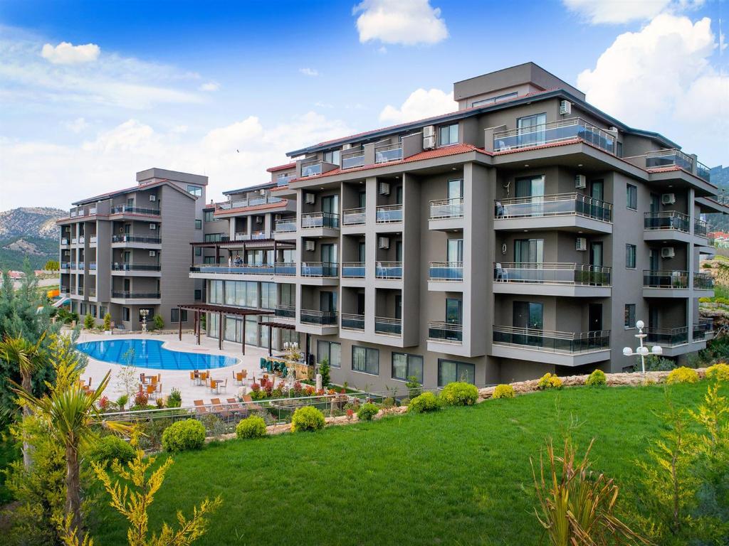 an apartment building with a pool and a lawn at Hierapark Thermal & SPA Hotel in Pamukkale