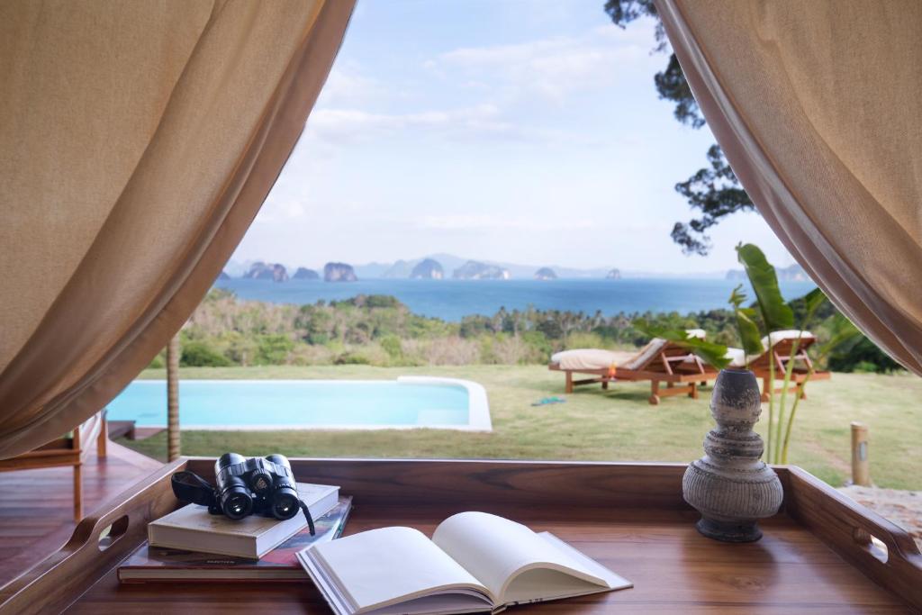 a window with books and a view of a pool at Koyao Island Resort in Ko Yao Noi