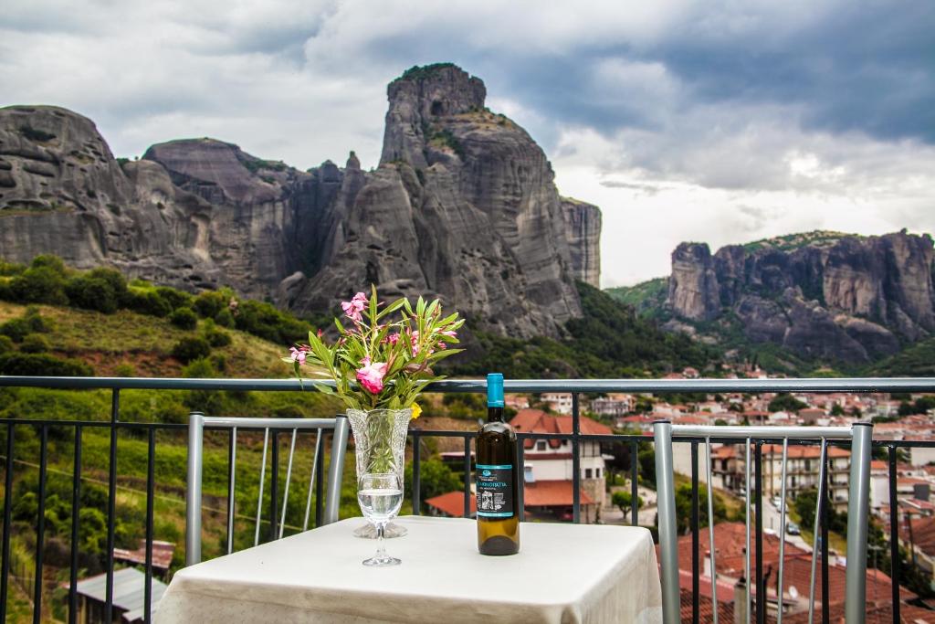 a table with a bottle of wine and a vase with flowers at Chrysorama Rooms in Kalabaka