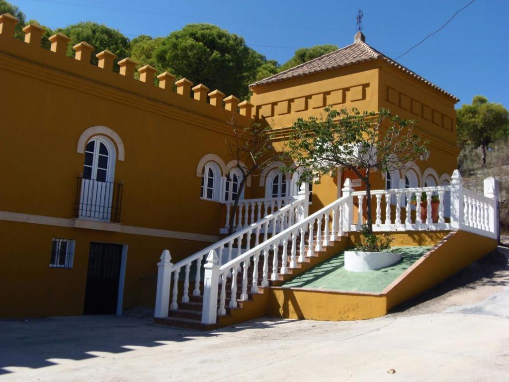 a yellow building with a staircase and a white fence at Hostal La Parada in Bornos