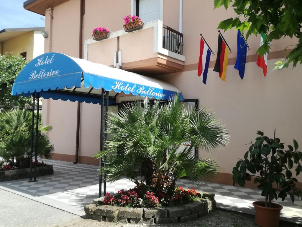 a building with a blue umbrella and some flags at Bellerive Ristorante Albergo in Manerba del Garda