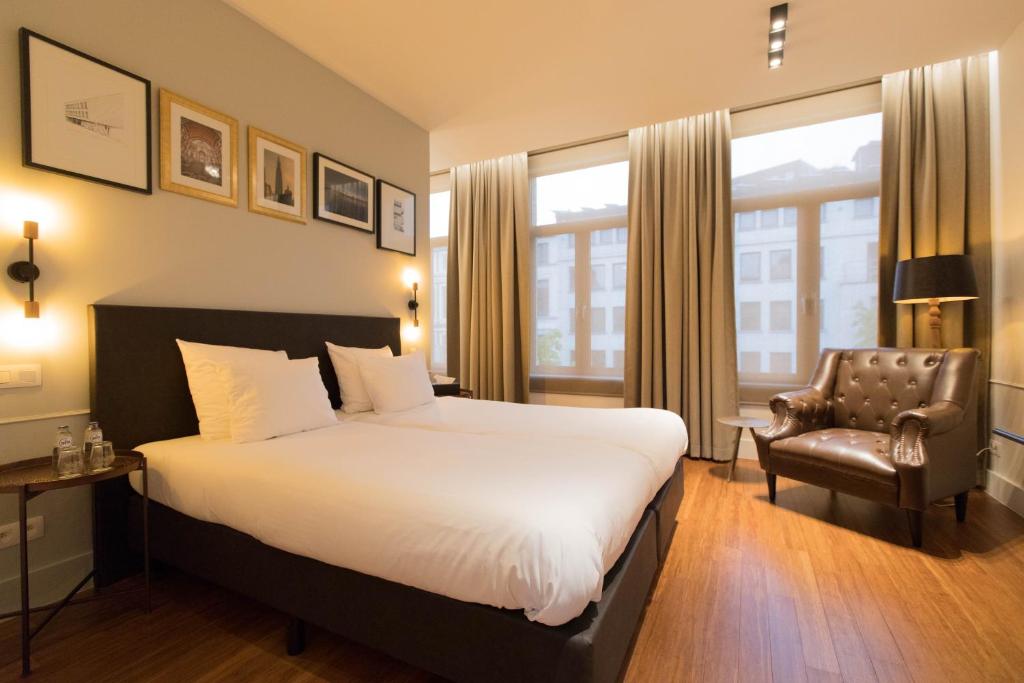 アントワープにあるBoutique hotel Maison Emileの大きなベッドと椅子が備わるホテルルームです。