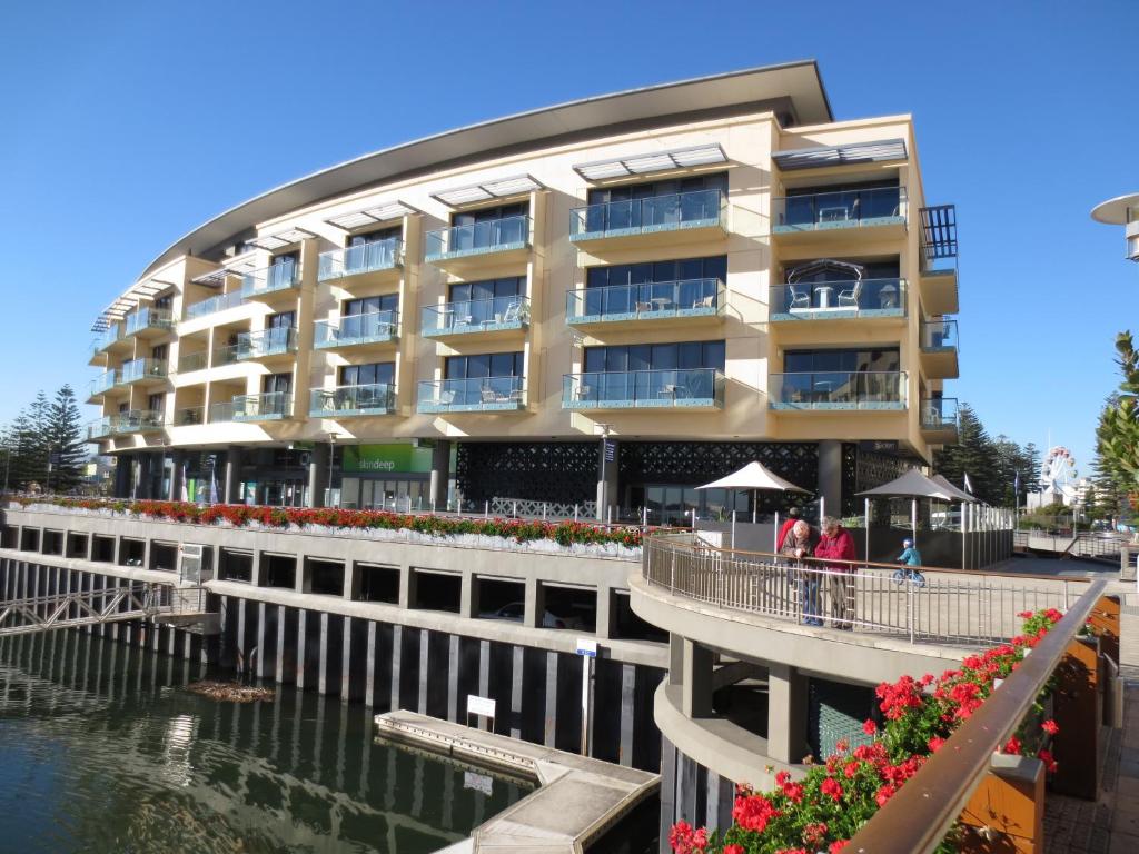 ein Gebäude mit einem Gehweg neben einem Wasserkörper in der Unterkunft Lights Landing Apartments in Adelaide