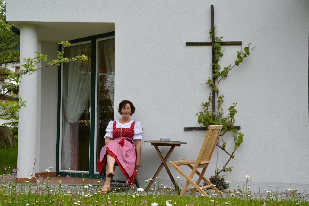 Eine Frau, die auf einem Stuhl vor einem Haus sitzt. in der Unterkunft Haus Dorothea in Söll