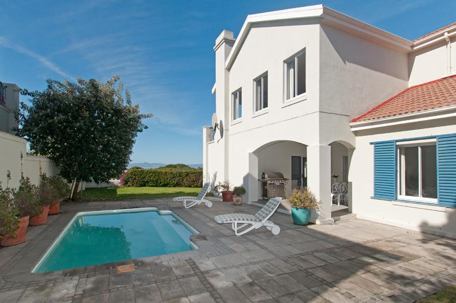 a villa with a swimming pool in front of a house at On The Rocks in Hermanus
