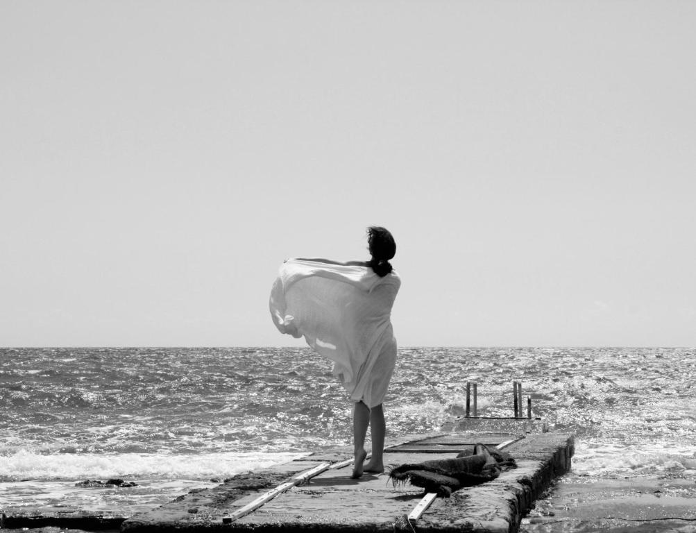 Una mujer parada en un muelle mirando al océano en Olosuites en Limassol
