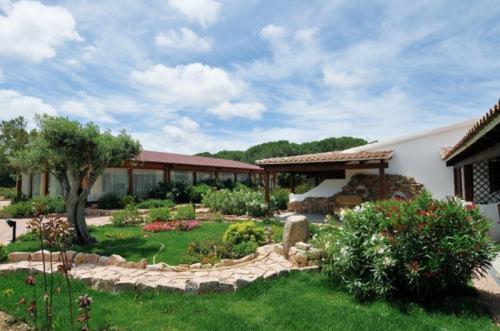 einen Garten vor einem Haus mit einem Gebäude in der Unterkunft Hotel Club Ragno D'oro in Aglientu