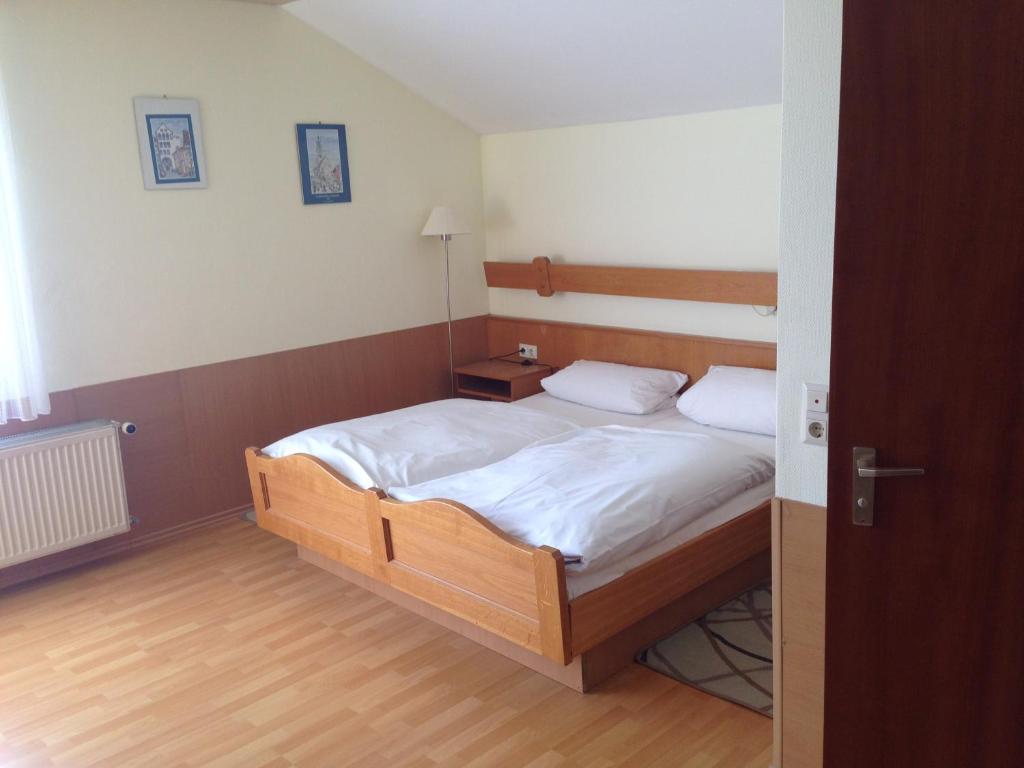 a bedroom with a bed with white sheets and wooden floors at Hotel Sonnenhof in Thannhausen