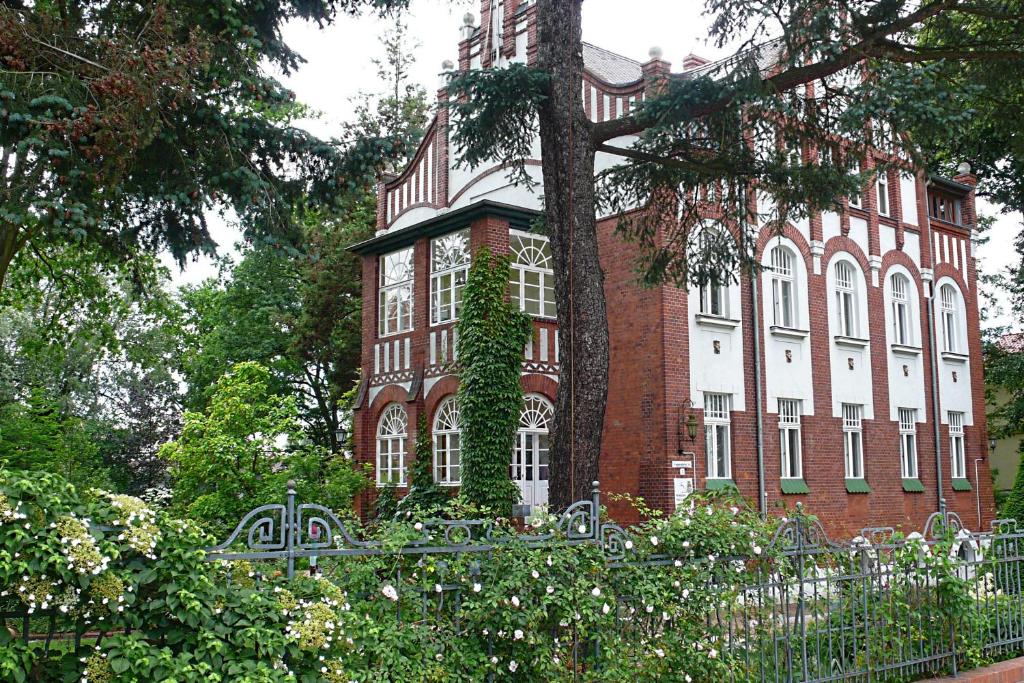 een groot bakstenen gebouw met een hek ervoor bij Pension Villa Fortuna in Lübben