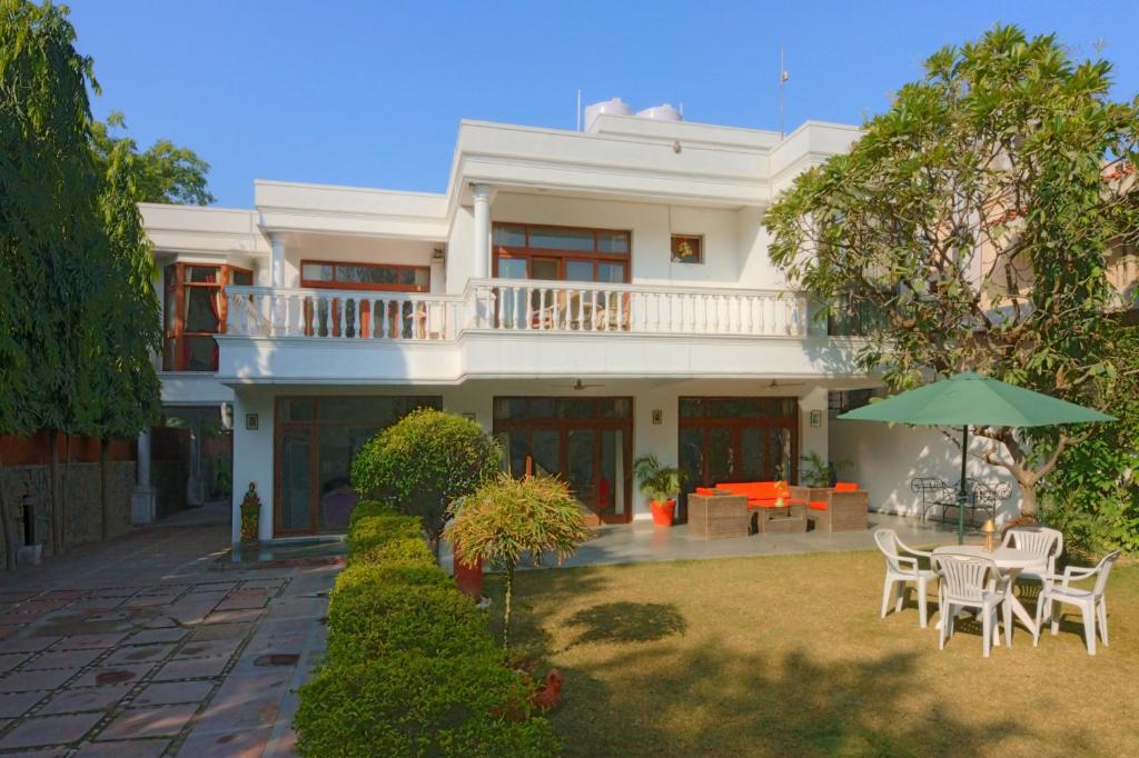 a white house with a table and chairs and an umbrella at The Stay Inn New Delhi in New Delhi