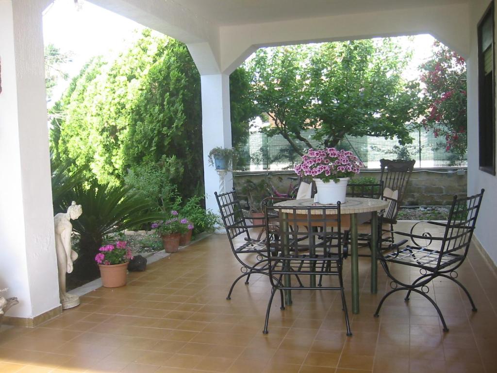 un patio con mesa, sillas y flores en La Via Del Mare, en Arenella