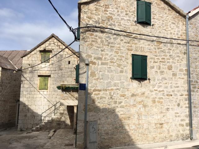 a brick building with green shutters on it at room Ami in Kaštela