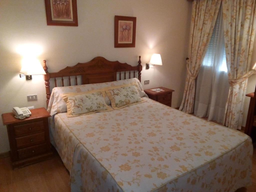 a bedroom with a bed with a phone and two night stands at Hotel Victoria in Zafra
